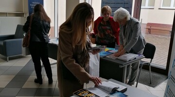 Uczestnicy seminarium przy stoisku Biblioteki z publikacjami dostępnymi do korzystania w Bibliotece