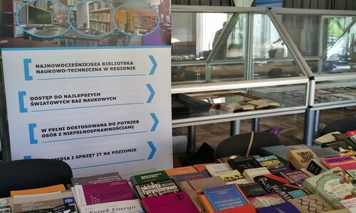 Baner biblioteki a przed nim st&oacute;ł z wydawnictwami